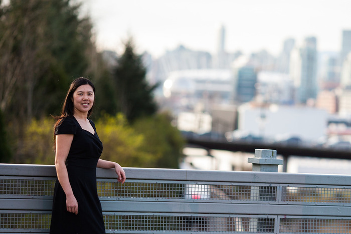 A portrait of Belinda Li with the Vancouver skyline in her background.